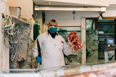 A man wearing a white dress shirt, black tie, with raw meat in his hand
